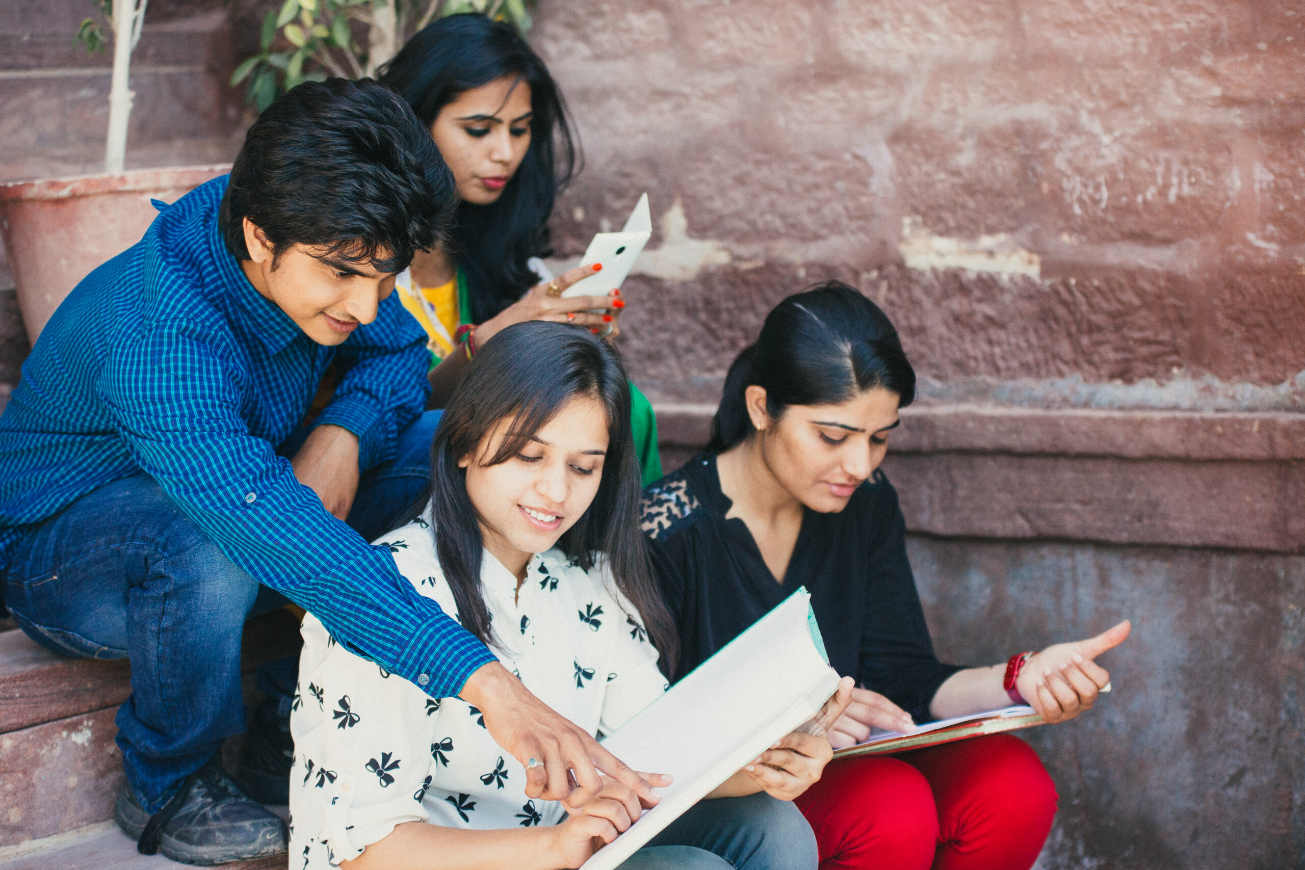 Four Indian students studying together while sitting on staircase steps.